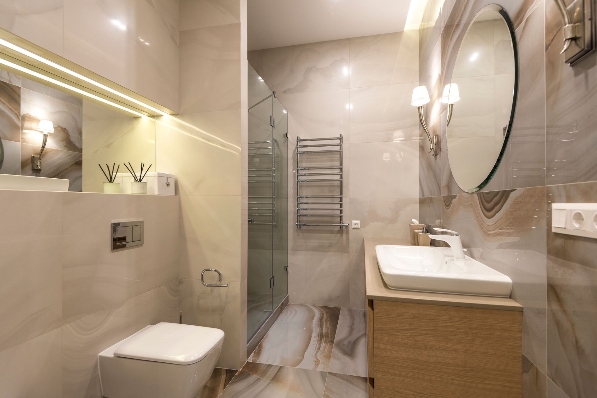 Elegant bathroom with marble tiles, large mirror, and modern fixtures.